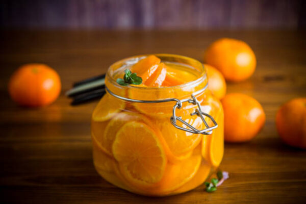 Sweet tangerine jam in a glass jar on a wooden table