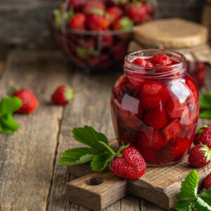 Homemade strawberry jam in jar, wooden rustic background, copy space