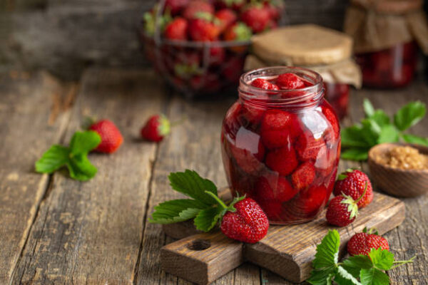 Homemade strawberry jam in jar, wooden rustic background, copy space