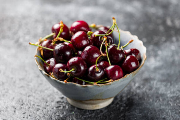 Cherries in a plate on a dark concrete background close up