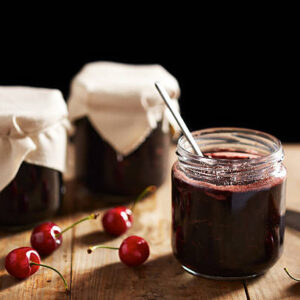 Homemade cherry jam in jars on wooden table