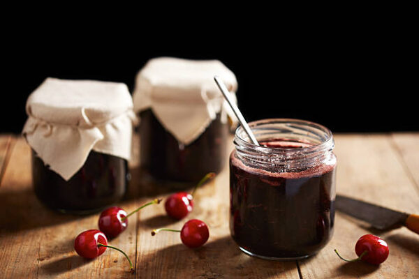 Homemade cherry jam in jars on wooden table