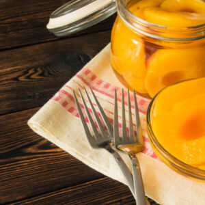 Peach canned in a glass jar and bowl on a dark wooden background
